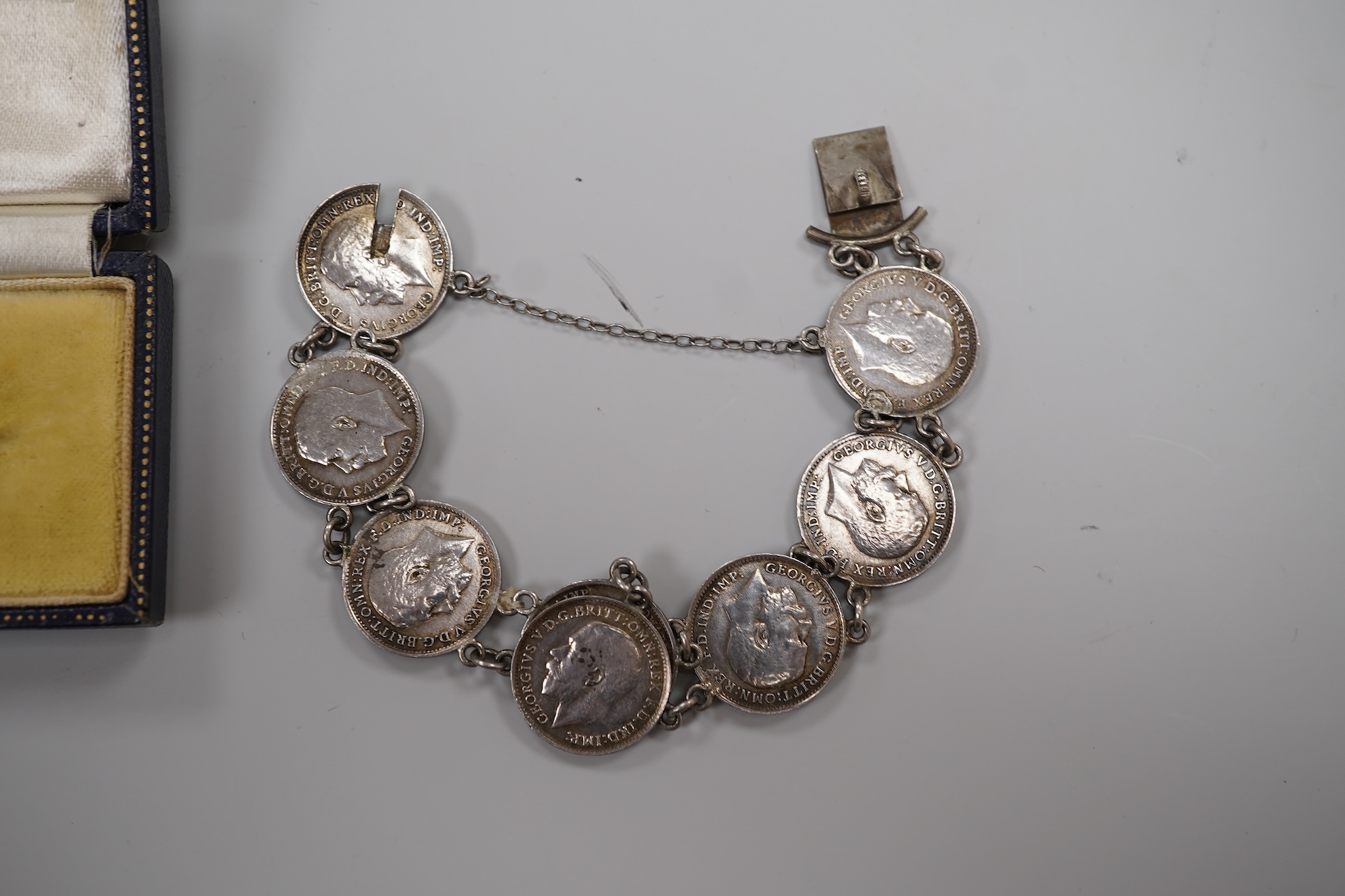 A cased early 20th century 9ct and single stone split pearl set bar brooch, 42mm and a white metal coin bracelet.